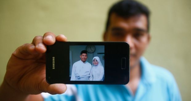 Mohamad Sharil Shaari (36), nephew of Razahan Zamani, a passenger on the missing Malaysian Flight MH370, shows a wedding picture that he took of Razahan and ... - image