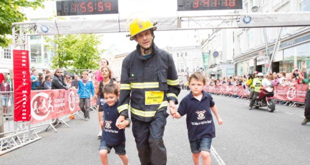  Leon and Noah O’Shea pass the finish line with their father, Cork firefighter Alex O’Shea,  as he sets a new Guinness World Record for running a marathon in full firefighting gear in a time of 3 hours 41 minutes and 10 seconds. In the Cork Marathon today, Alex shaved almost 58 minutes off the previous record set at the London Marathon earlier this year. Photograph: Darragh Kane