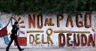 A woman walks past a graffiti that reads “No to the debt payment” in Buenos Aires. Photograph: Marcos Brindicci/Reuters