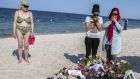 Women pray near bouquets of flowers laid on the beach of the Imperial Marhaba resort, which was attacked by a gunman, in Sousse on Sunday. Photograph:  Zohra Bensemra/Reuters  