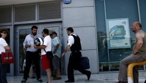 A security guard delivers cash to a closed National Bank of Greece SA bank branch as customers wait outside in Athens, Greece. Photograph: Kostas Tsironis/Bloomberg