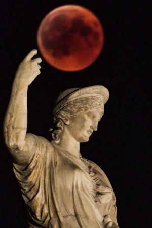   The moon is shown next to a statue of the ancient Greek goddess Hera in central Athens. Photo: AFP PHOTO / Aris MESSINISARIS MESSINIS / AFP / Getty Images
