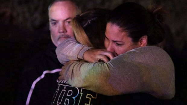 Une femme qui a fui le Borderline Bar and Grill, où un homme armé a tué 11 personnes, est prise dans les bras par des proches à Thousand Oaks, en Californie. Photographie: Mike Nelson / EPA