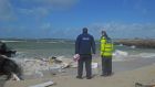 Gardaí from Clifden Garda station survey the wreckage from the caravan that was washed into the sea at Claddaghduff. Photograph: Conor Mc Keown