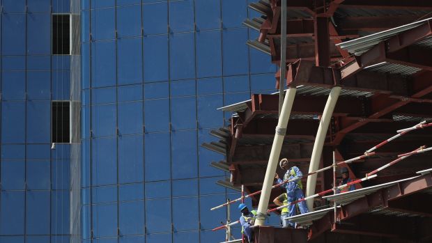 Workers maneuver a part into place on a construction site in the budding new financial district in Doha. Photo: Sean Gallup/Getty Images