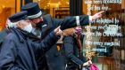 A doorman gives directions to a pedestrians wearing a face mask-due  along a busy shopping street in Dublin on Tuesday. Photograph: Paul Faith/AFP