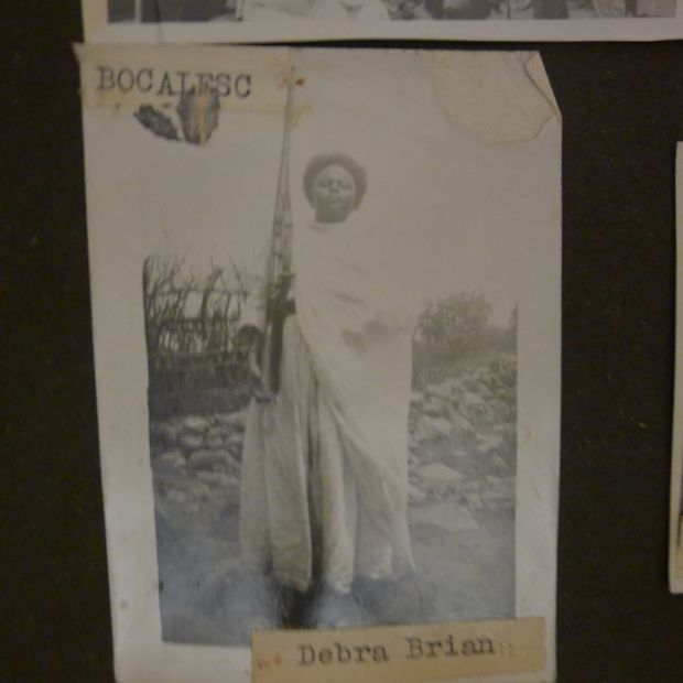 Bogalech from Debre Berhan is fully clothed in her traditional Ethiopian dress. She has a shawl draped across one shoulder and stands with her chin raised, a rifle in her hand.