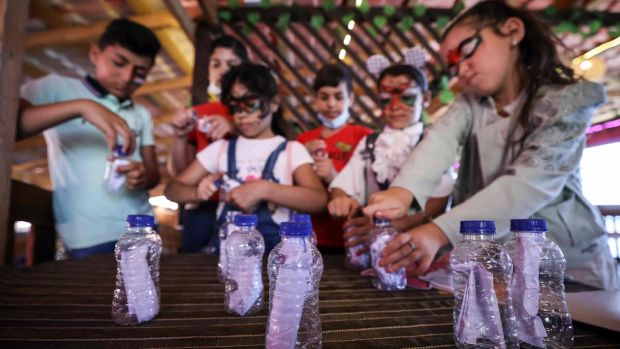 Palestinian students in Gaza  who received letters from US children, prepare messages in bottles as a response. Photograph:  Mahmud Hams/AFP via Getty