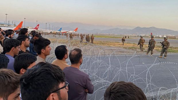 Afghans crowd at the airport as US soldiers stand guard in Kabul on Monday. Photograph: Shakib Rahmani/AFP via Getty Images