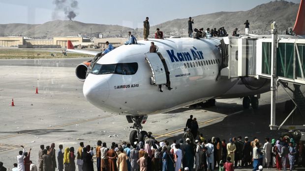 Afghan people climb on top of an aircraft as they wait at the Kabul airport on Monday. Photograph: Wakil Kohsar/AFP via Getty Images