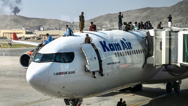 People climb atop a plane as they wait at the airport in Kabul to flee Afghanistan. Photograph: Wakil Kohsar/AFP/Getty Images