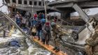 Ukrainian  soldiers help citizens cross a destroyed bridge as they flee from the frontline town of Irpin, near Kyiv, on Monday. Photograph: Roman Pilipey/EPA