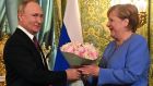 Russian leader Vladimir Putin welcoming then German chancellor Angela Merkel with a bouquet of flowers during their meeting at the Kremlin in August 2021. Photograph: Evgeny Odinokov/Sputnik/AFP via Getty