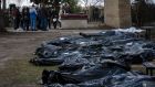 A family mourns a relative killed during the war, as dozens of black bags containing more bodies of victims are strewn across the graveyard in Bucha, on the outskirts of Kyiv, Ukraine. Photograph: Rodrigo Abd/ AP Photo