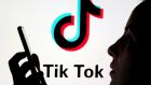 A person holds a smartphone as Tik Tok logo is displayed behind. Photograph: Dado Ruvic/Reuters