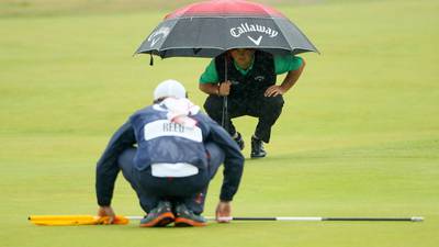 Caddies carry the load as world’s best golfers battle the elements