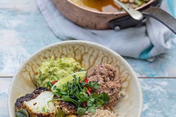 Whole baked cauliflower burrito bowl with refried beans and guacamole