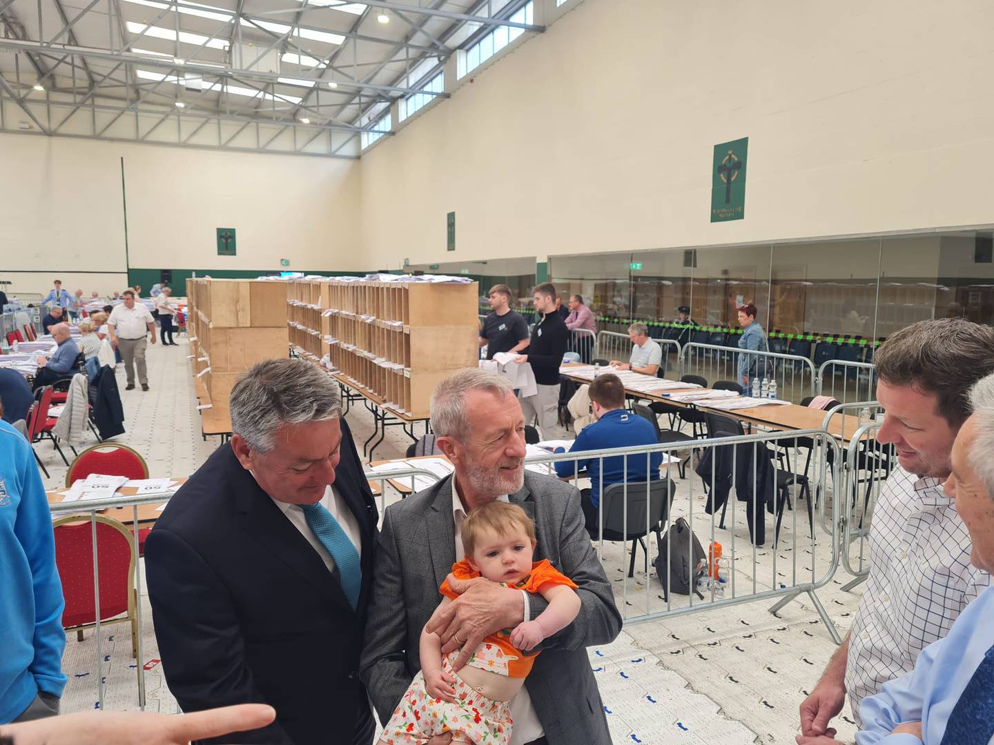Sitting Ireland South MEPs Billy Kelleher and Sean Kelly holding his granddaughter, Hannah Rose Kelly, home from Australia at the Nemo Count Centre on Monday. Photograph: Barry Roche