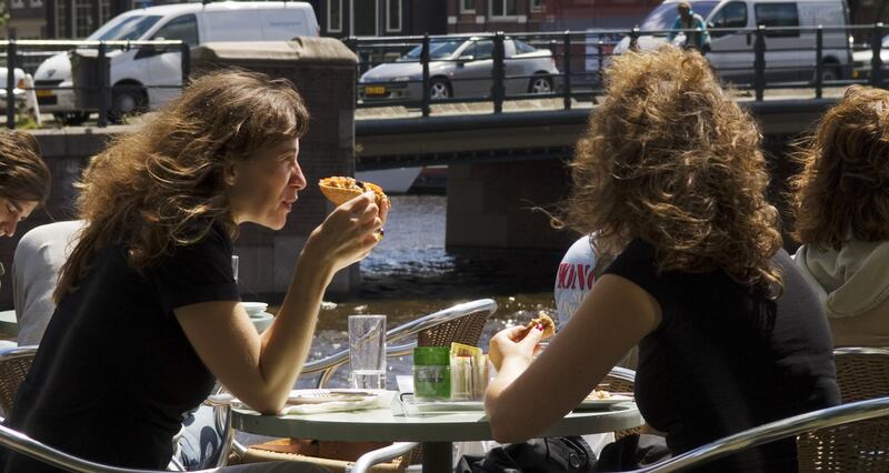 Patrons sit along Kloveniersburgwal canal at Cafe De Jaren in central Amsterdam.