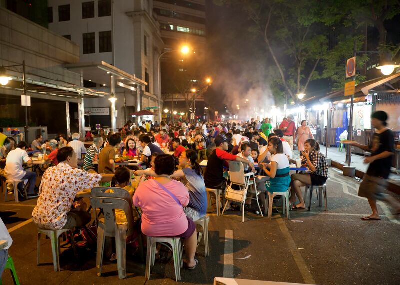 Singapore by night: people eating satay on the street. Photograph: Getty