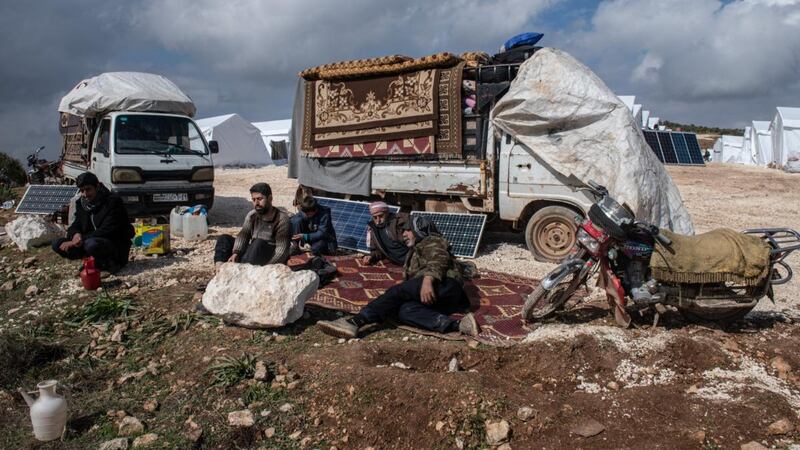 Displaced Syrians sit in front of trucks loaded with their possessions at a newly build camp near village of Atmeh in Idlib. Photograph: Burak Kara/Getty Images