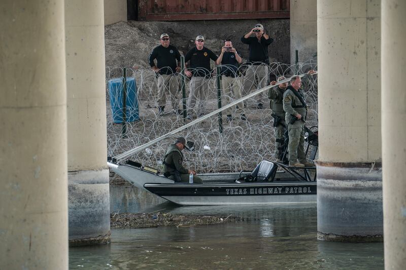 Law enforcement officers stand near concertina wire on the bank of the Rio Grande river. Photograph: Go Nakamura/New York Times
                      