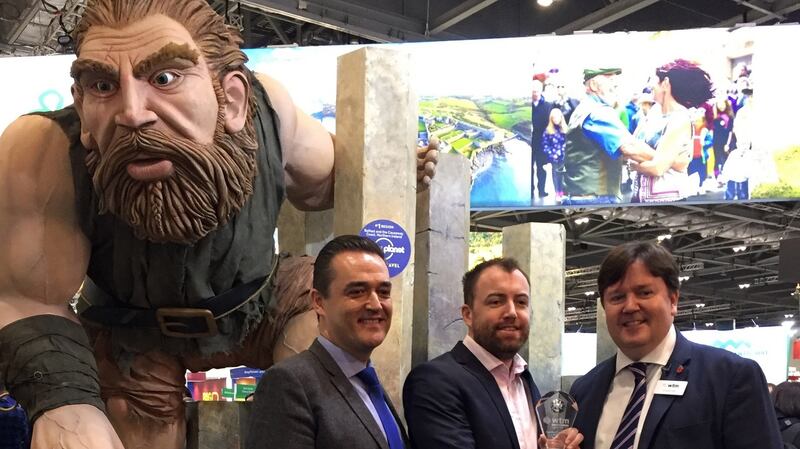 David Wood and Cormac Ó Suilleabháin, both from Tourism Ireland, accept the award for ‘best stand feature’ from Jonathan Hull from World Travel Market (right) as giant Finn McCool looks on. Photograph: Tourism Ireland