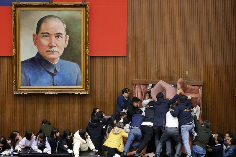 Lawmakers from the main opposition Kuomintang (KMT) (in white) try to break into Parliament where Democratic Progressive Party (DPP) occupied the night to avoid the passing of the third reading of amendments to the Civil Servants Election and Recall Act and other controversial bills at the Legislative Yuan in Taipei. Photograph: I-Hwa Cheng/AFP