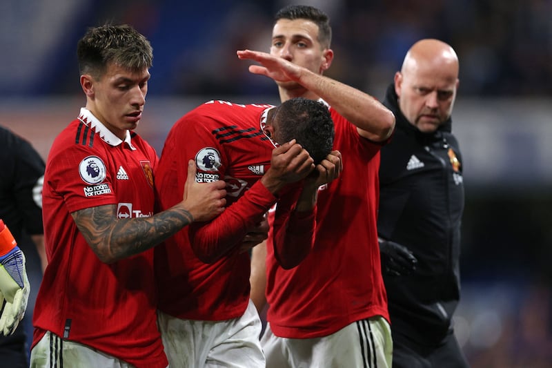 Manchester United's French defender Raphael Varane is consoled by team-mates Lisandro Martinez and Diogo Dalot as he leaves the pitch after picking up an injury during the Premier League game against Chelsea at Stamford Bridge. Photograph: Adrian Dennis/AFP via Getty Images