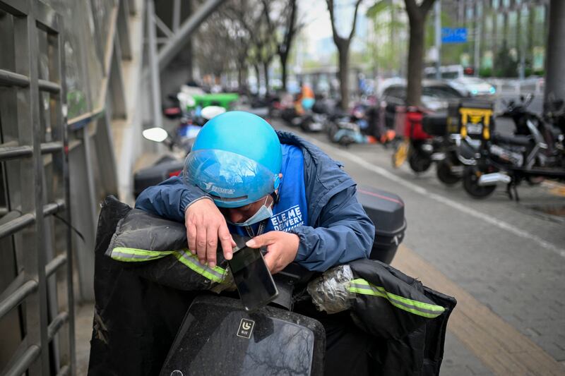 A Beijing food delivery worker rests briefy: There is growing concern in China the profits of delivery platforms come at the cost of the welfare of drivers. Photograph: Wang Zhao/AFP