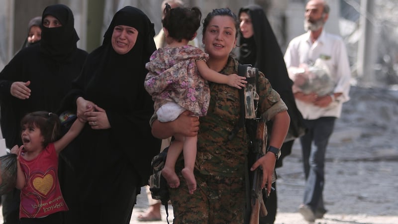 A Syria Democratic Forces (SDF) fighter helps civilians who were evacuated by the SDF. The SDF has said Islamic State was using civilians as human shields. Photograph: Rodi Said/Reuters