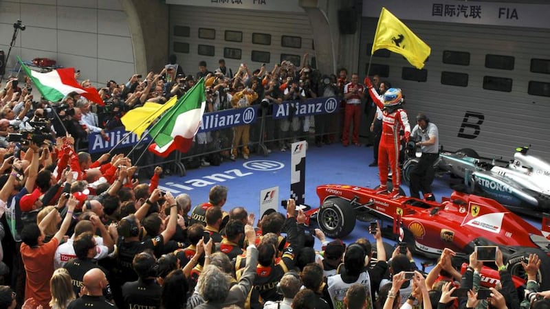 Ferrari Formula One driver Fernando Alonso of Spain waves the team flag as he stands on top of his car to celebrate his win at the Chinese F1 Grand Prix at the Shanghai International Circuit. Photograph: Reuters