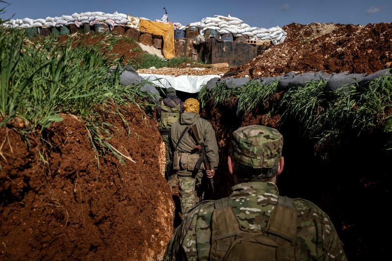 Fighters for the militant group Hayat Tahrir al-Sham make their way through a trench on the front lines near the town of Maaret al-Nasaan, Idlib Province, Syria. Photograph: Ivor Prickett/New York Times
                      