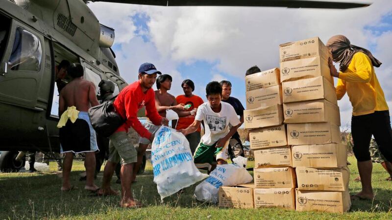 Residents of the destroyed island of Homonhon, near Taclabon, offload the first batch of food aid from an army helicopter in the aftermath of Typhoon Haiyan. Photograph:  Kevin Frayer/Getty Images