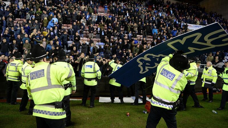 An advertising board is thrown at police as they attempt to prevent a pitch invasion after the  FA Cup  match between Wigan Athletic and Manchester City at DW Stadium. Photograph: Gareth Copley/Getty Images