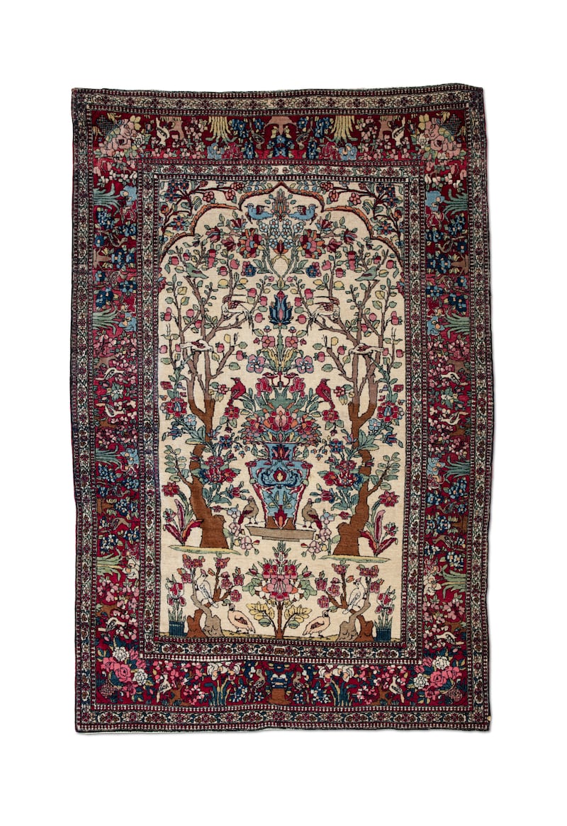 A Tree-of-Life Isfahan rug circa 1890-1900 decorated with elaborate foliage and birds framing a central vase.