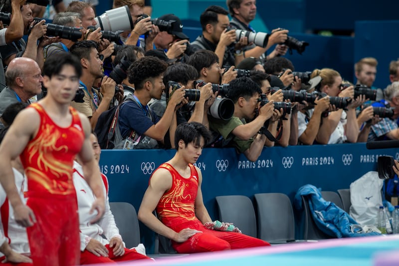 Photographers concentrate on the gold medal-winning Japanese team as Su Weide of China sits dejected after his two falls on the horizontal bar helped tip the contest. Photograph: Tim Clayton/Corbis via Getty Images