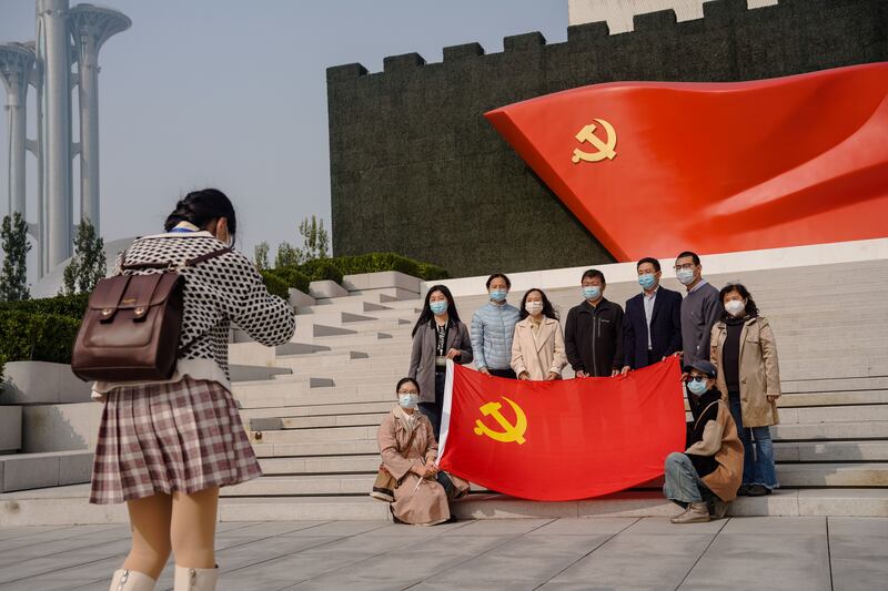 People wearing face masks pose for a photo holding the flag of the Communist Party of China. Photograph: Wu Hao/EPA