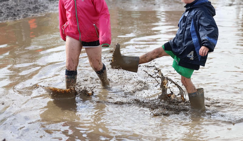 A pair of children splash around in the wet and the mud on day one of the event. Photograph: Dara Mac Dónaill/The Irish Times