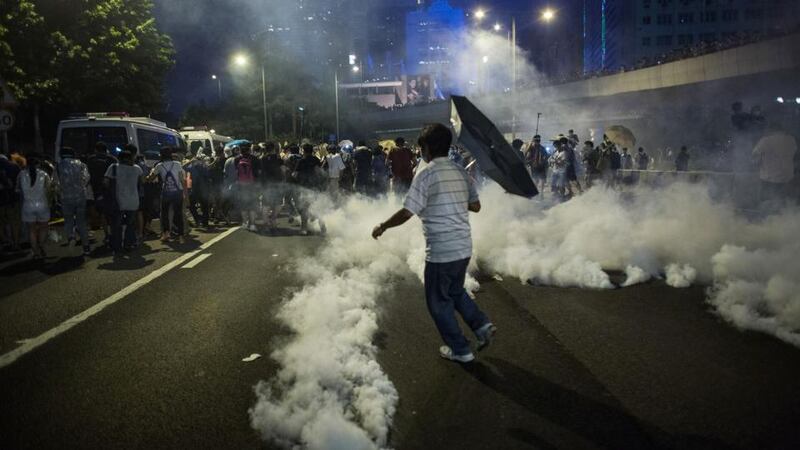 Demonstrators disperse as tear gas is fired by police during a protest near central government offices in Hong Kong, China, on Sunday, Sept. 28, 2014. Thousands of Hong Kong pro-democracy demonstrators defied tear gas and pepper spray to occupy the city center, as police undertook the biggest crackdown since the city returned to Chinese rule. Photographer: Lam Yik Fei/Bloomberg