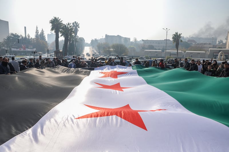 People celebrate holding a large Syrian opposition flag at Umayyad Square in Damascus. Photograph: Omar Haj Kadour/AFP/Getty Images