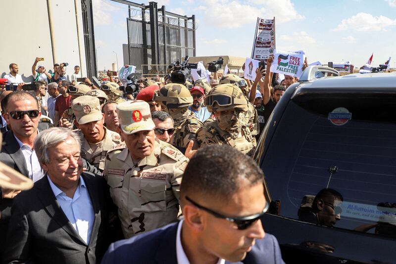 Protesters raise signs in solidarity with Palestinians in the Gaza Strip as Egyptian army officers and bodyguards escort UN secretary-general Antonio Guterres during his visit to oversee preparations for delivery of humanitarian aid to the Palestinian enclave, on the Egyptian side of the Rafah border, on Friday. Photograph: Kerolos Salah/AFP/Getty 