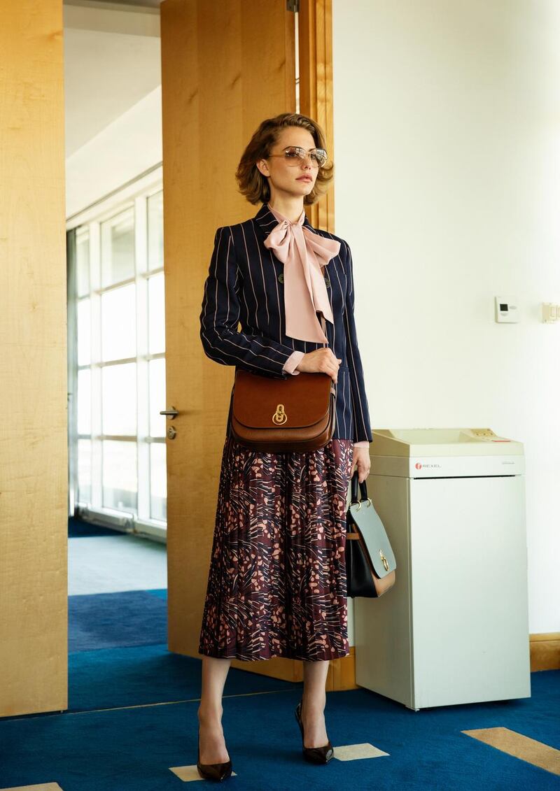 Navy pinstripe jacket €715, printed pleated skirt €510 both Victoria Beckham, pink bow blouse €160 MaxMara, frames €420 Chanel, handbag €1,495, crossbody bag €1,150 both Mulberry, burgundy patent shoes €170 Kurt Geiger London, all from Brown Thomas