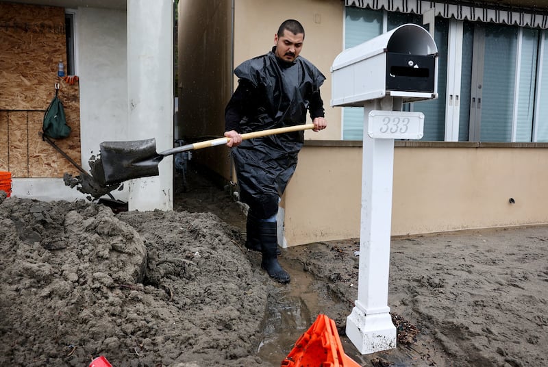 Clean-up worker Jovani Barboza clears away sand which washed up from the beach in front of homes on January 11th, 2023 in Aptos, California. Photograph: Mario Tama/Getty Images