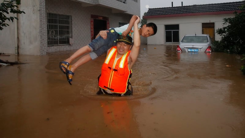 In this photo taken on  July 2nd, 2016, a rescue worker lifts a child through flood waters as residents are evacuated after the Jushui river broke the dyke and flooded Tuhe village in Wuhan in central China’s Hubei province. Photograph: AP