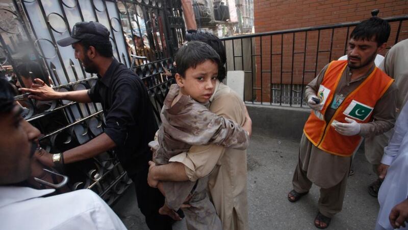 A man carries his injured  son to hospital in Peshawar following today’s bombing. Photograph: Fayaz Aziz/Reuters