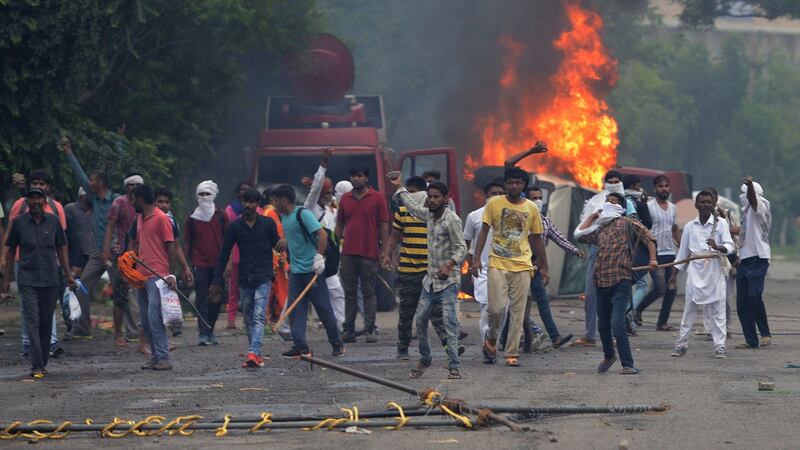 Supporters of Indian religious leader Gurmeet Ram Rahim Singh throw stones at security forces next to burning vehicles during clashes in Panchkula on Friday. Photograph: Sharma Money/AFP/Getty Images