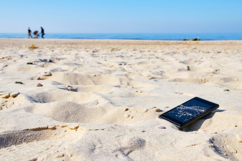 Mobile phone with broken screen in sand on a beach. Photograph: Getty