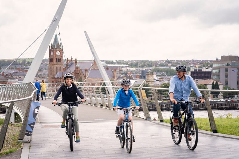 Family cycling over Peace Bridge, Derry