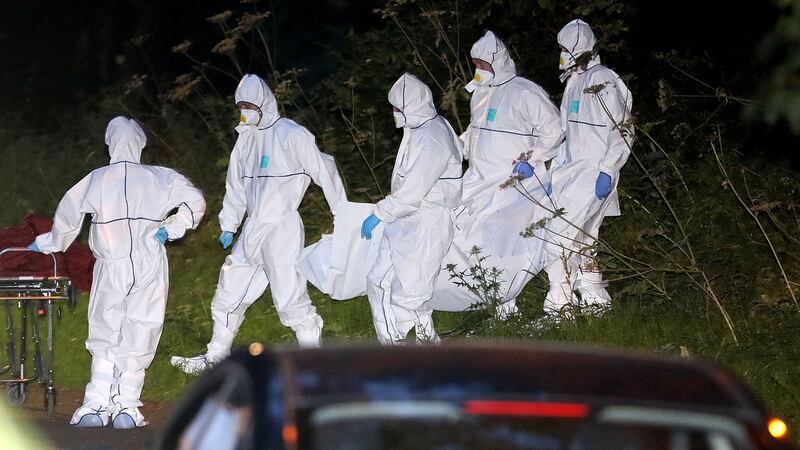 Members of a Garda forensics team remove a body from the scene at Coolmine Woods on Monday night. Photograph: Collins